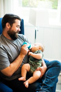 Dad feeding baby through baby bottle