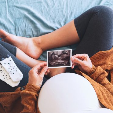 Pregnant woman holding ultrasound image