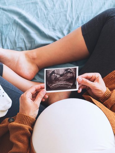 Pregnant woman holding ultrasound image