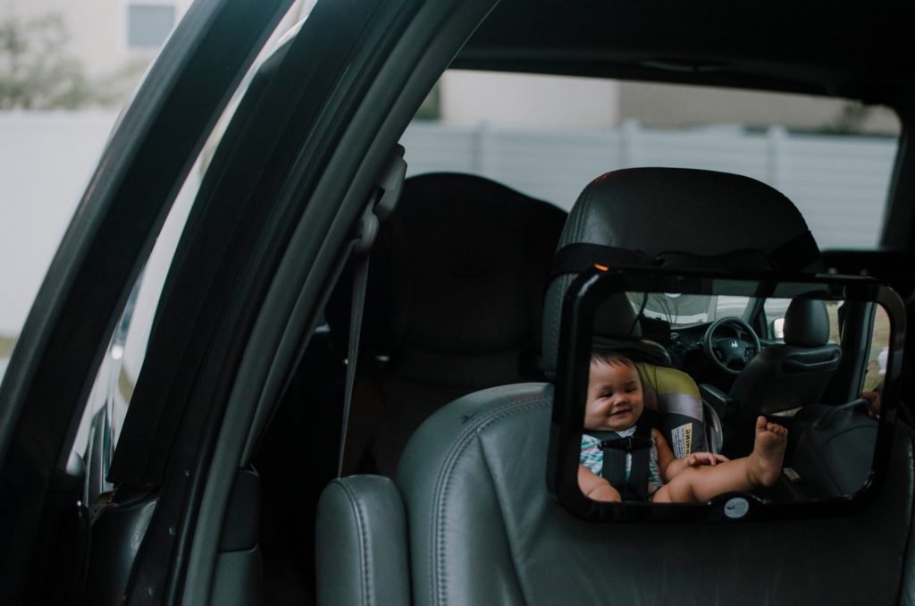 Baby looking into mirror in car seat, rear faced