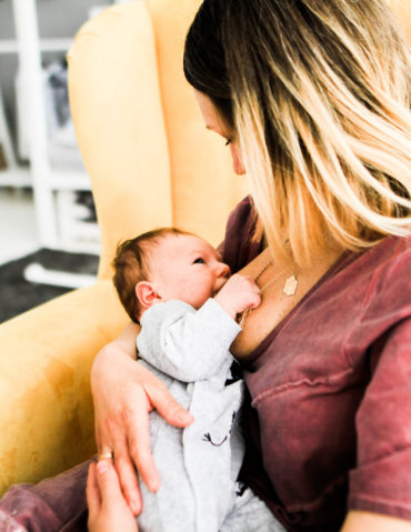 Mother looks at her baby breastfeeding