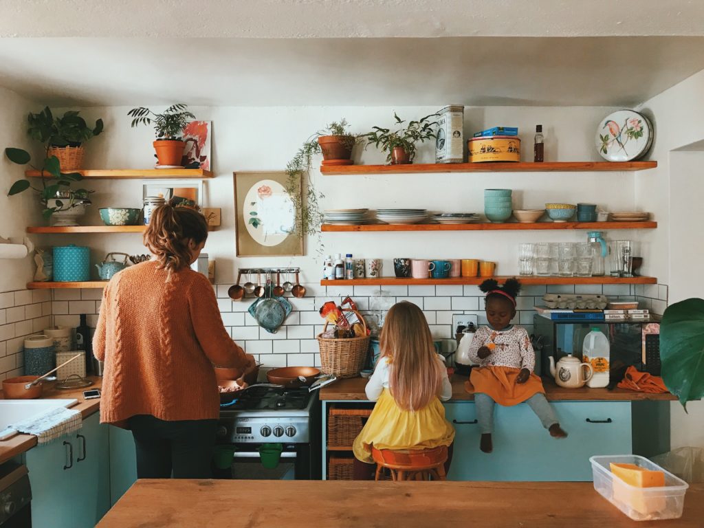 Two little girls help mom out in the kitchen