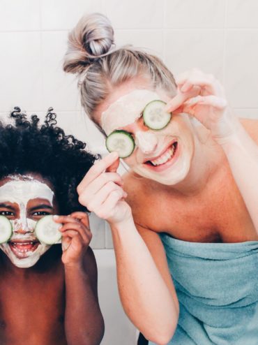 Woman and toddler smile with facemasks on holding cucumbers
