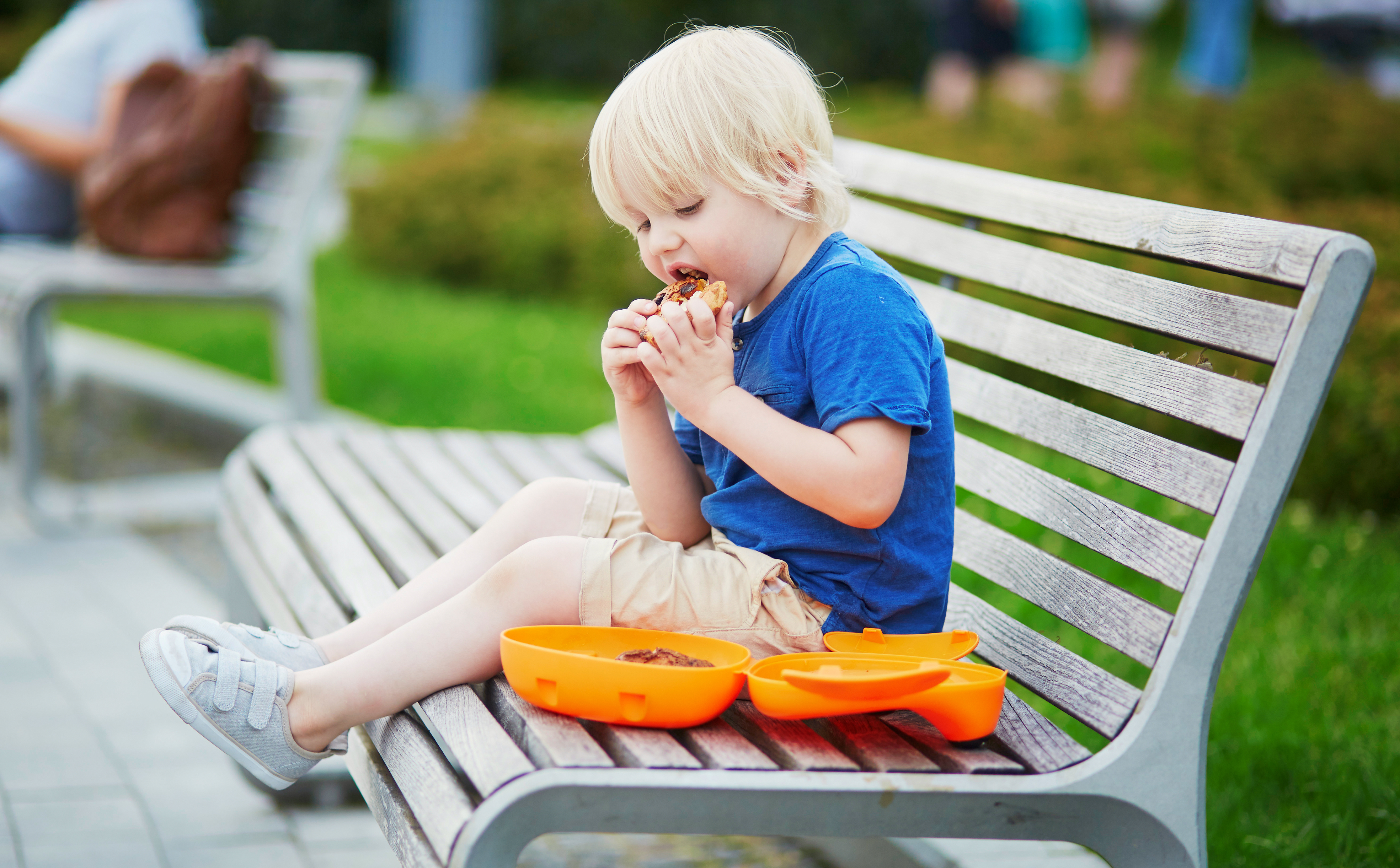Kid eating snack on a park bench
