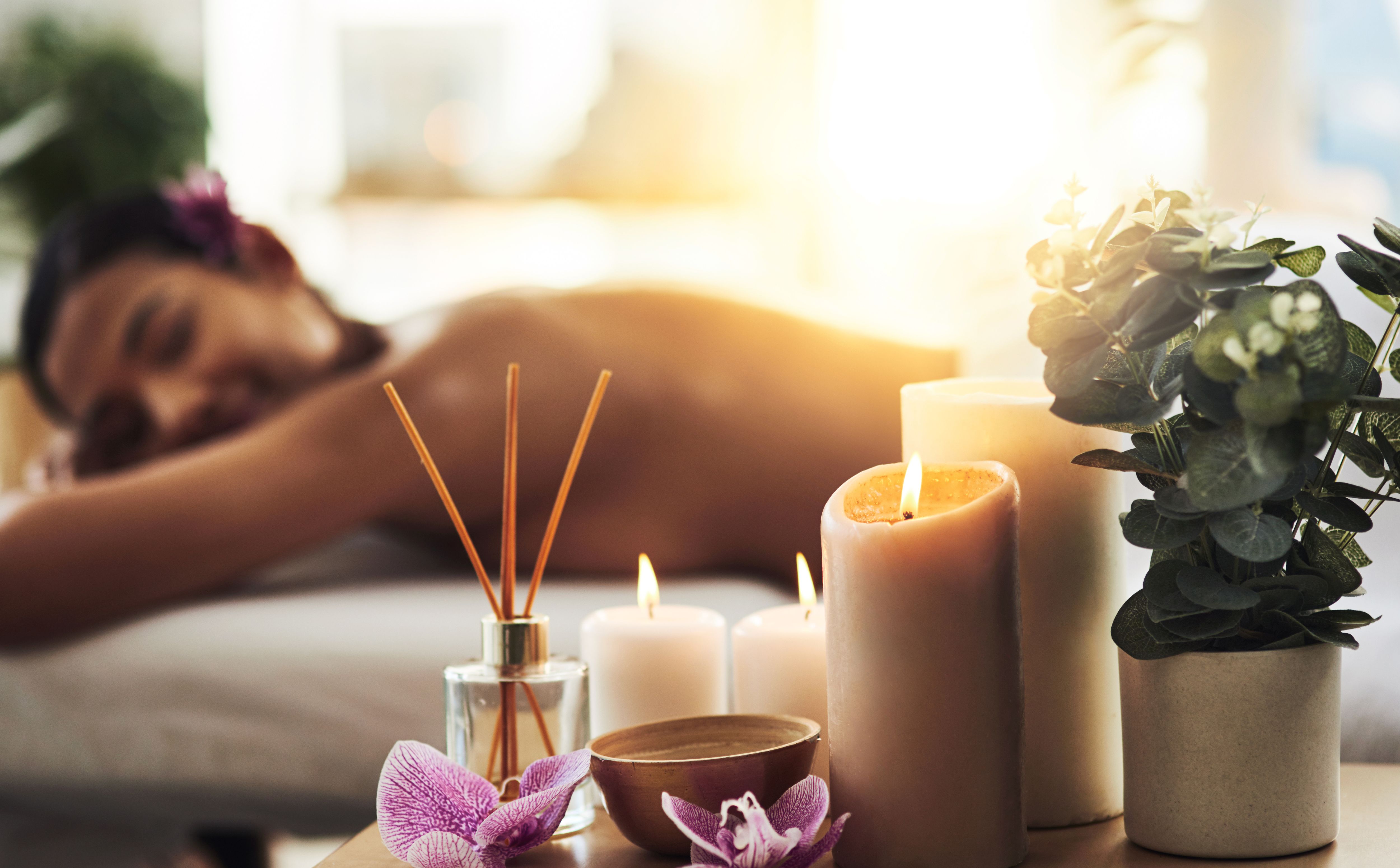 Women relaxing on a massage bed next to candles.
