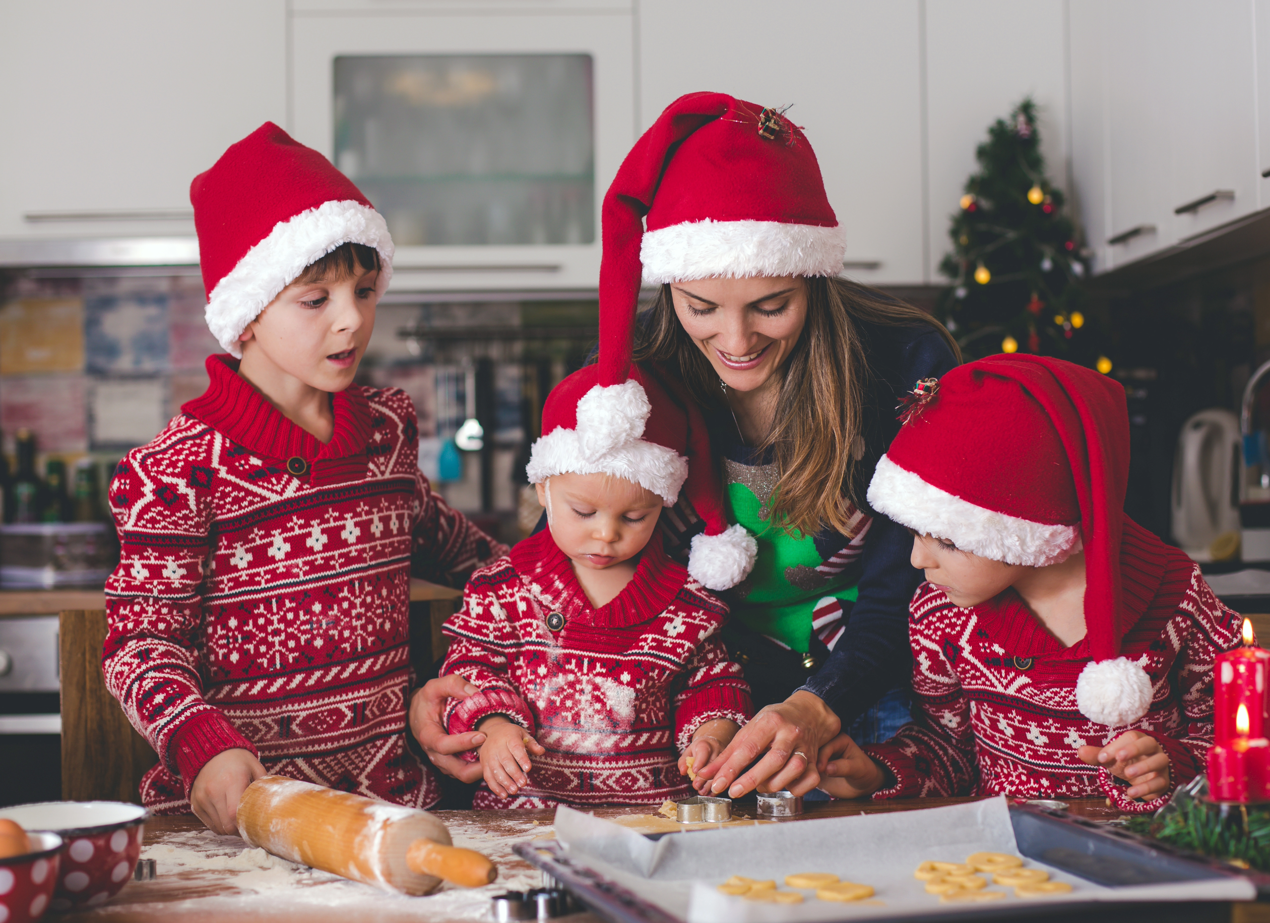 Family of four baking cookies with Christmas outfits.