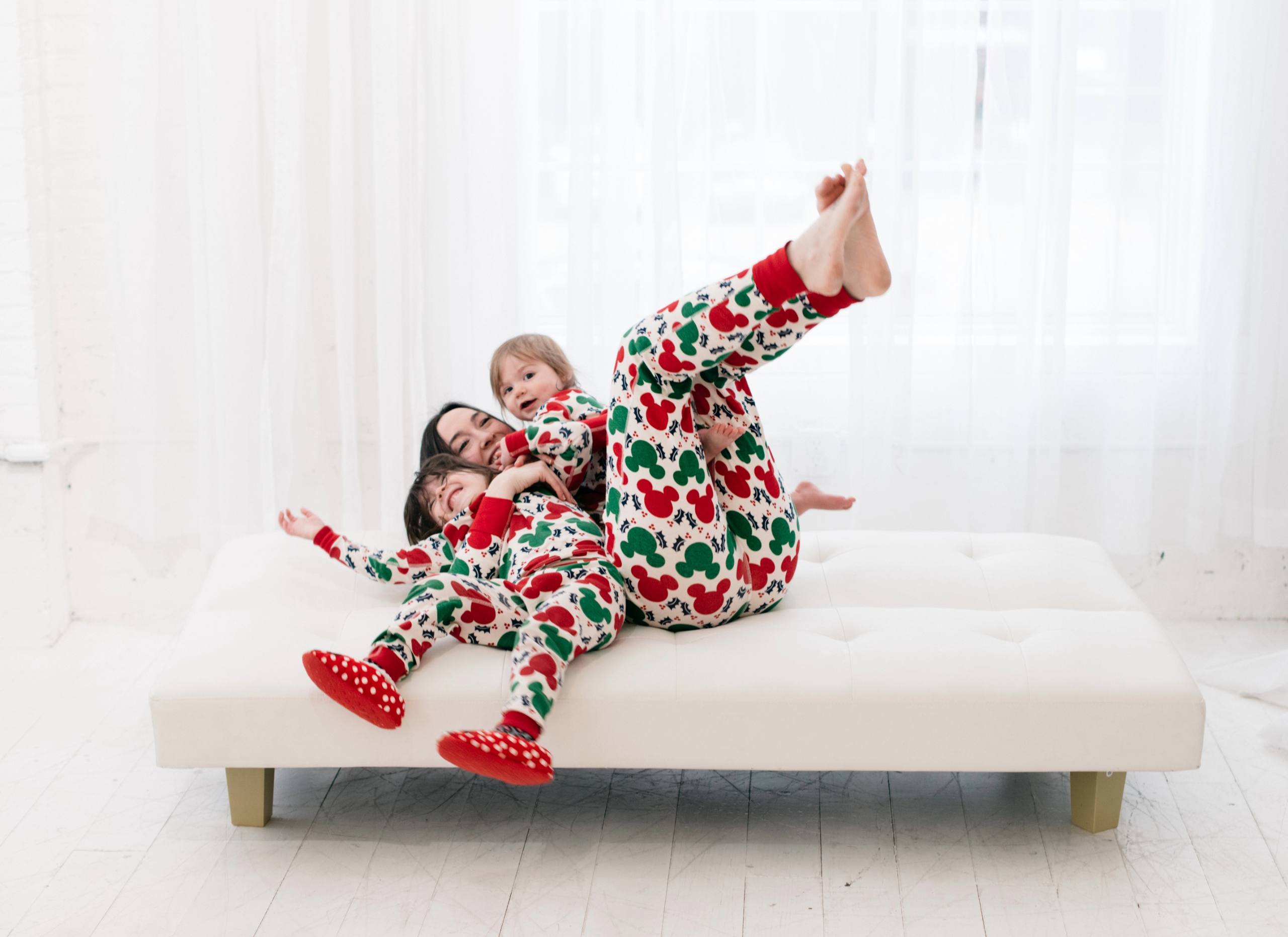 Family playing on the couch with matching Christmas pajamas.