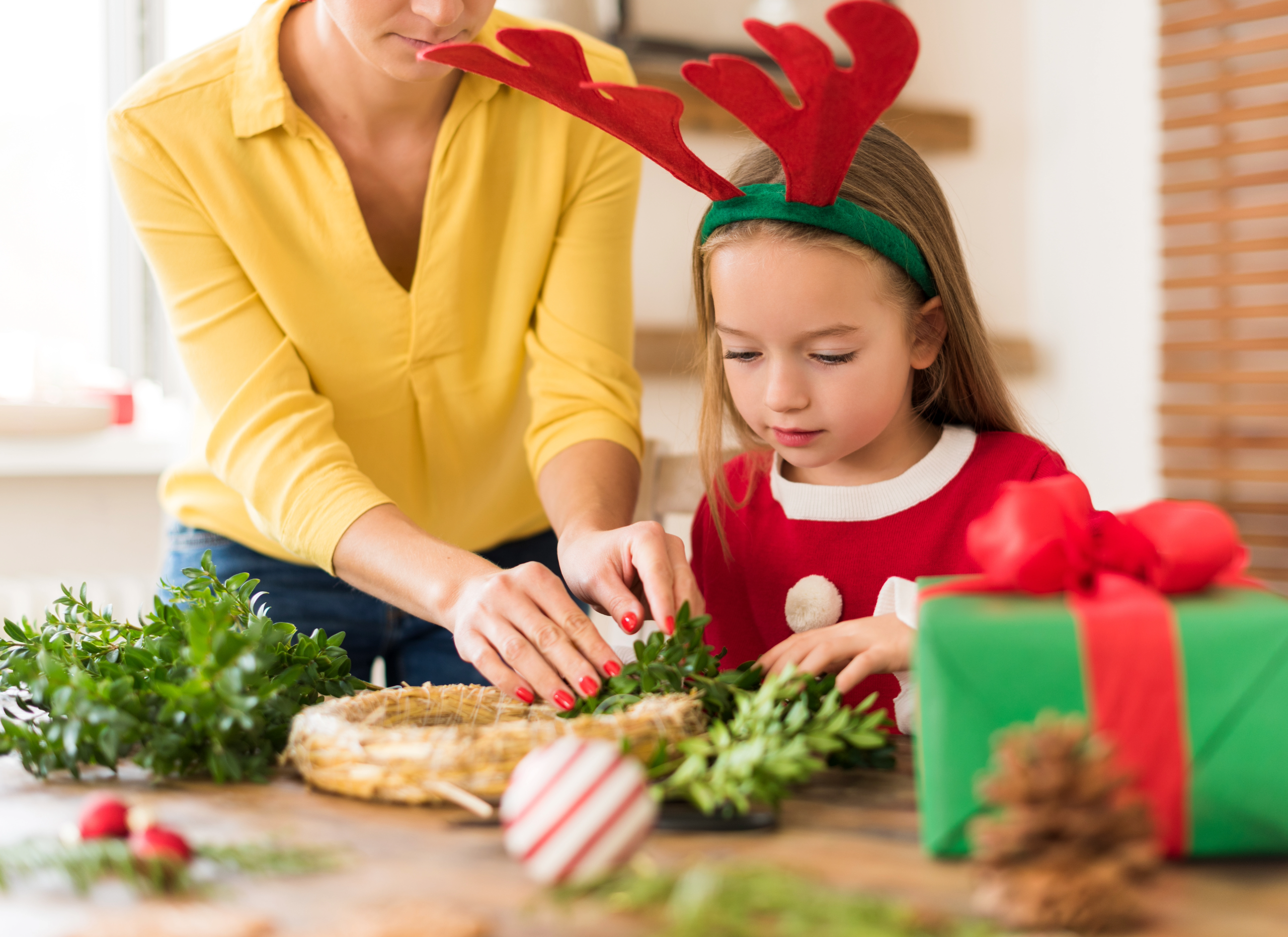 Mother and daughter making Christmas wreath.