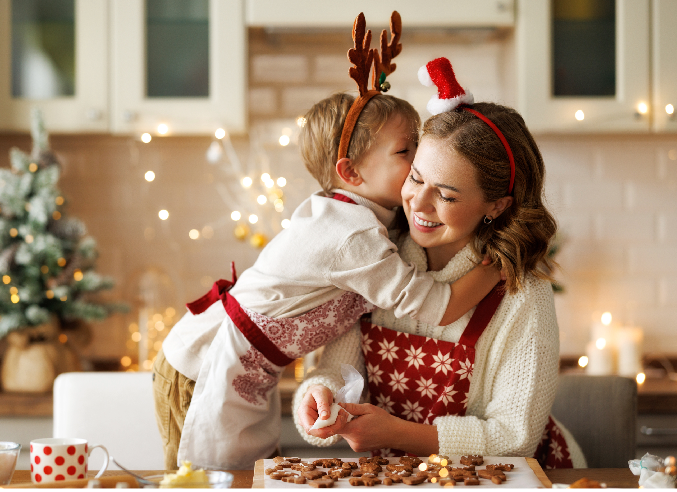 Son embracing mother while cocking Christmas cookies.