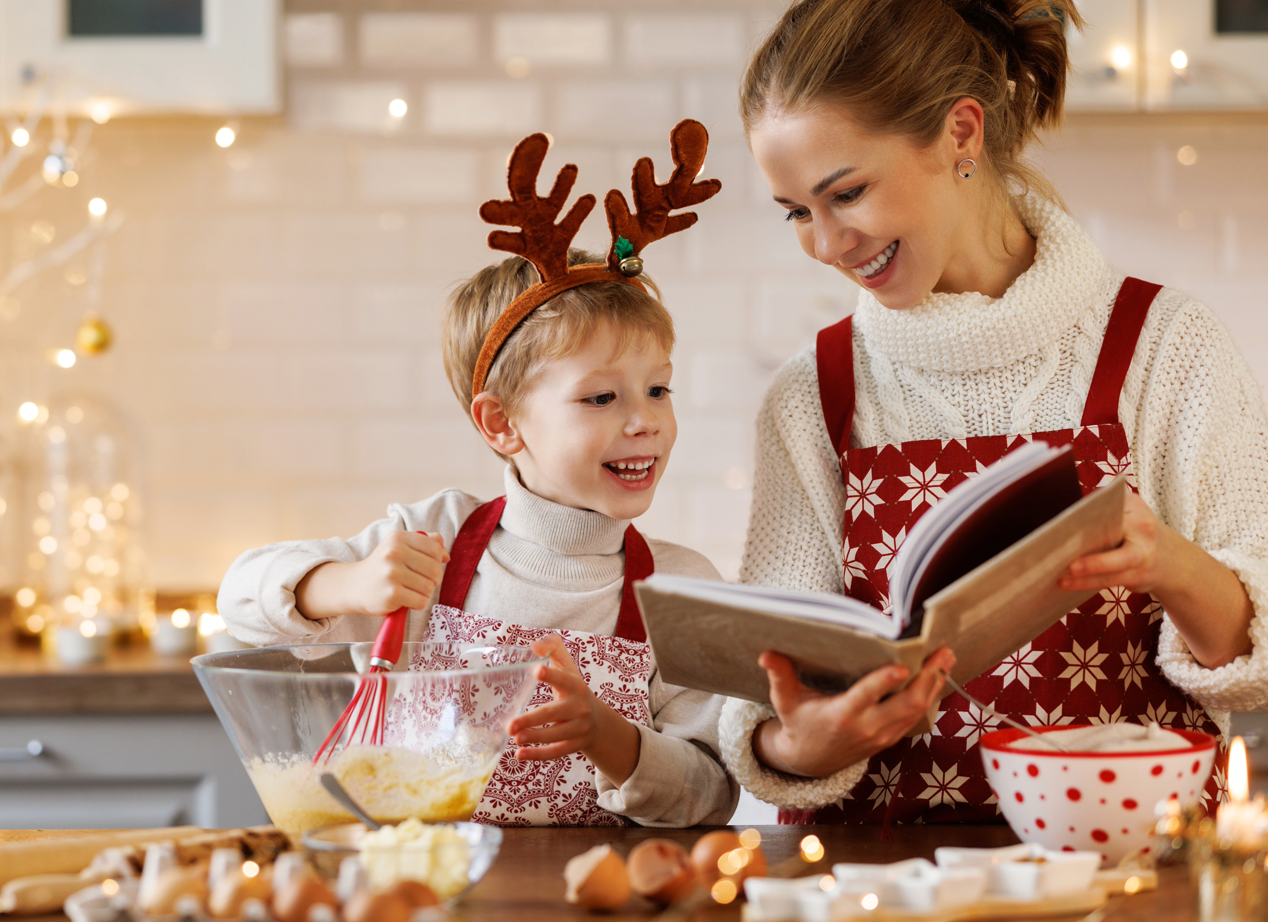 Toddler helping mother prepare Christmas recipe in the kitchen.