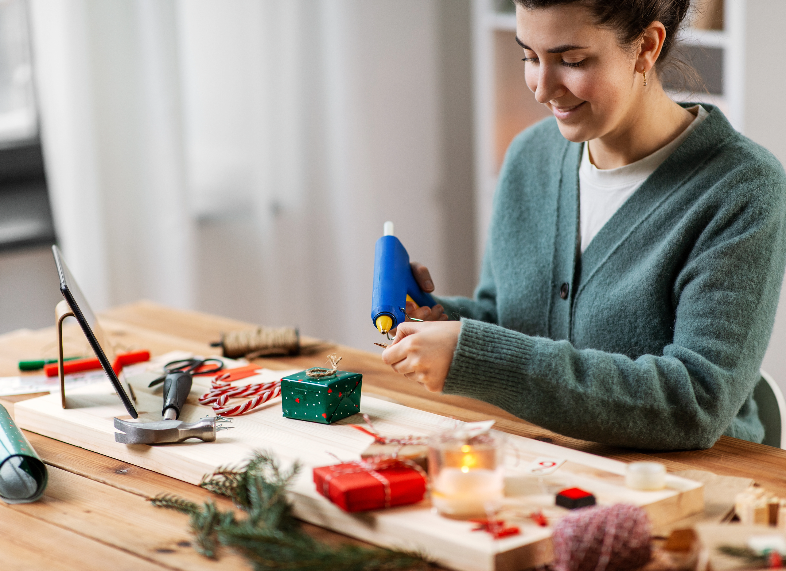 Women making a Christmas present using a hot glue gun.