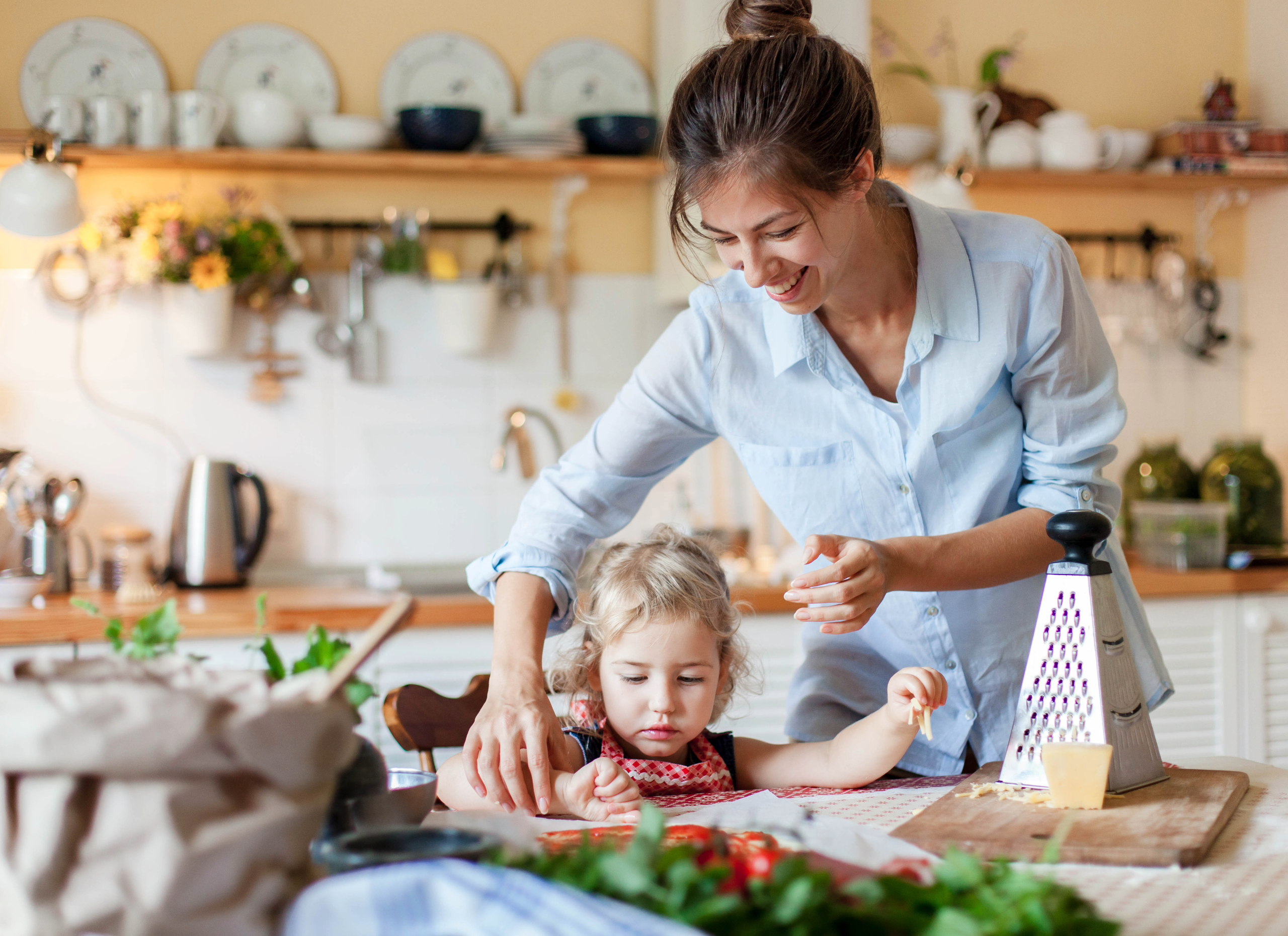 Mother and daghter making pizza in home kitchem