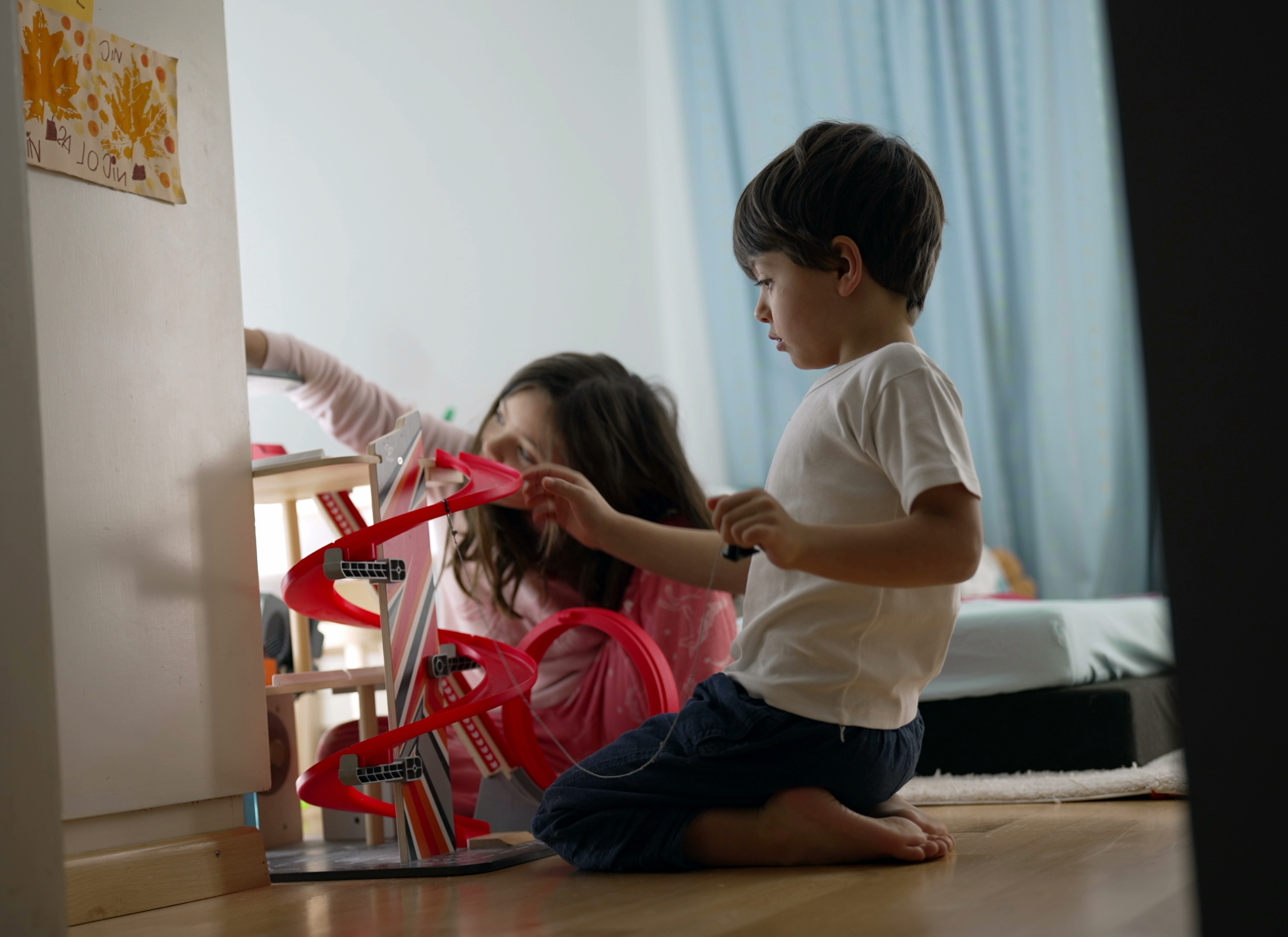 Mother playing toys with son in room before bedtime.